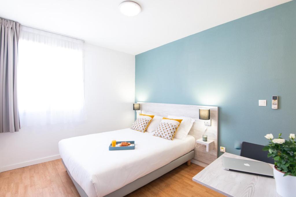 ein Schlafzimmer mit einem weißen Bett und einem Laptop darauf in der Unterkunft Zenitude Hôtel-Résidences Le Tholonet in Aix-en-Provence