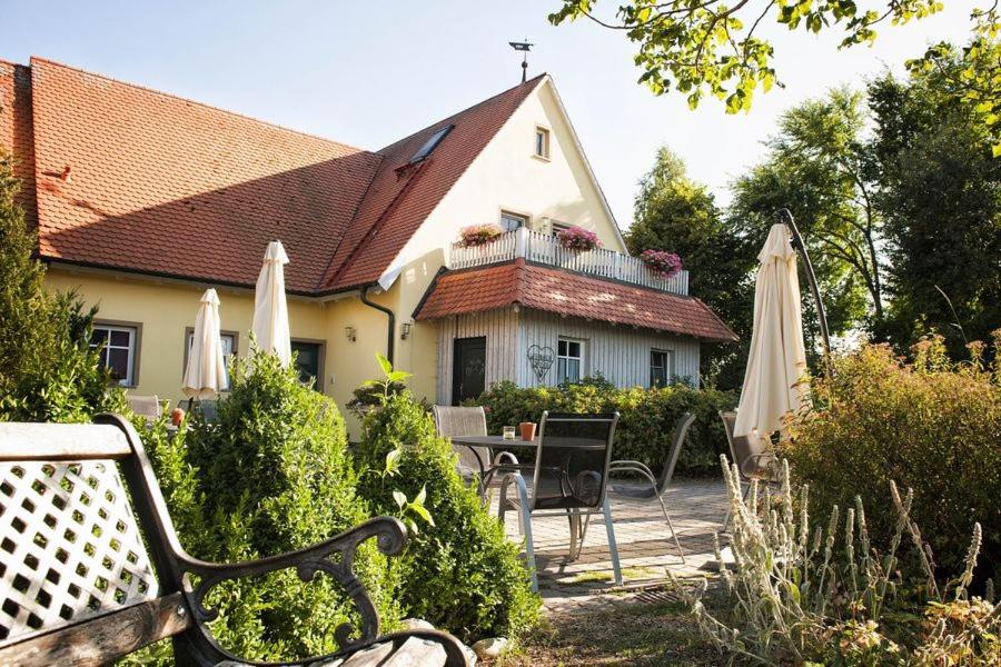 ein Haus mit einer Bank, einem Tisch und Sonnenschirmen in der Unterkunft Weinhof Grosch in Sugenheim