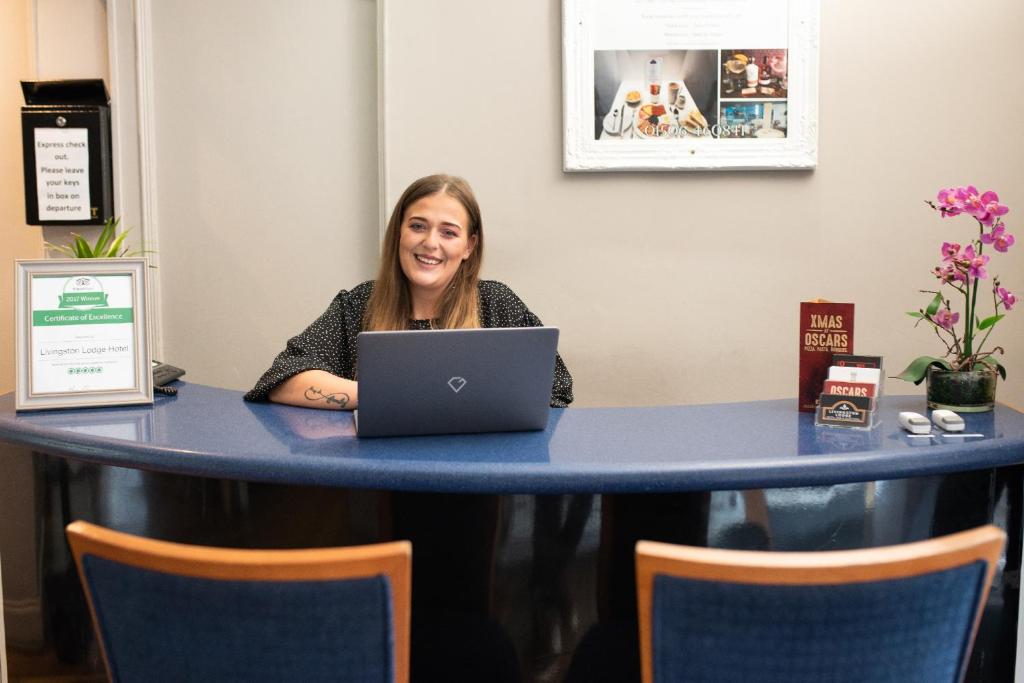 uma mulher sentada numa mesa com um laptop em Livingston Lodge Hotel em Livingston