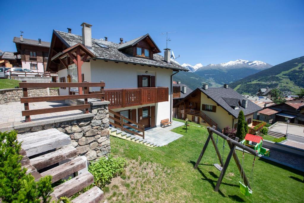 a house with a balcony with a view of the mountains at Appartamenti Baita Soliva in Oga