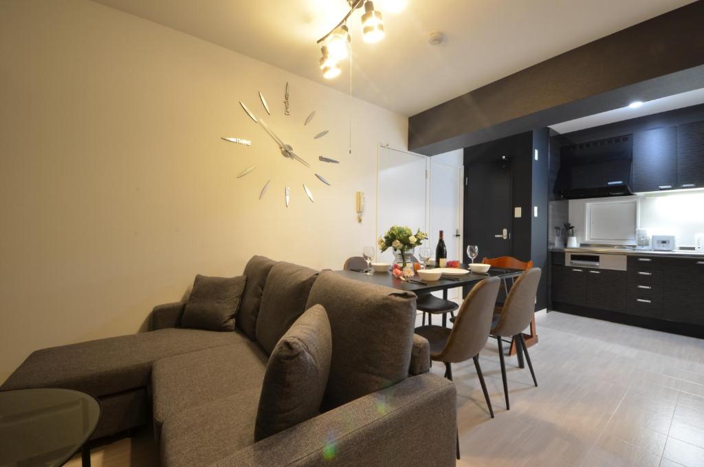 ein Wohnzimmer mit einer Couch und einer Uhr an der Wand in der Unterkunft River Side Namba 200 in Osaka