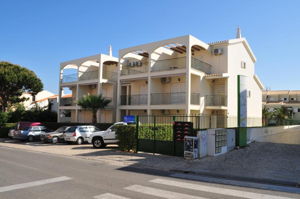 un edificio blanco con coches estacionados en un estacionamiento en Atlantico Sul, en Quarteira