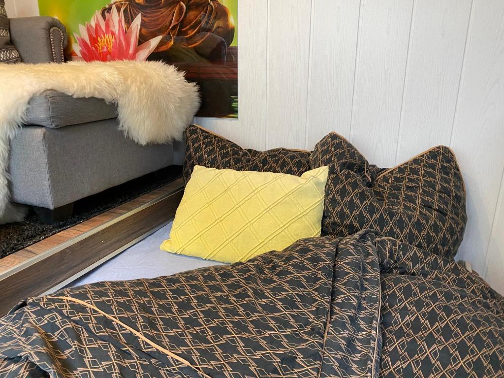 a couch with a blanket and a yellow pillow at Die Pilgerbox, Tiny House trifft Urlaub in Dahlem