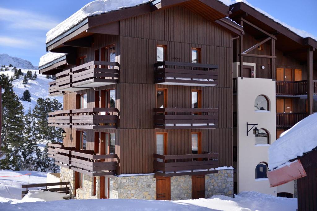 un bâtiment avec de la neige sur son côté dans l'établissement travelski home select - Résidence Licorne, à La Plagne