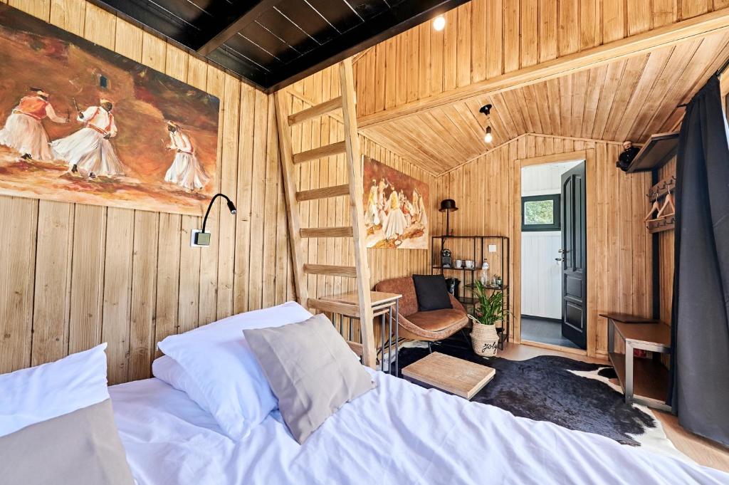 a bedroom with a bed in a room with wooden walls at Joly Tiny House in Overijse