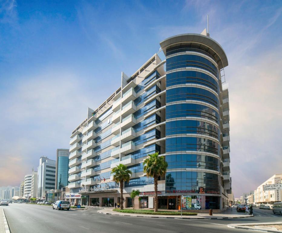 un edificio alto con una parte superior redondeada en una calle de la ciudad en Star Metro Deira Hotel Apartments, en Dubái
