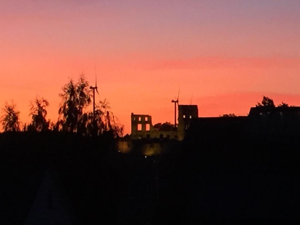a sunset with the silhouette of a building and trees at Ferienwohnung Mimi Souterrainwohnung in Kastellaun