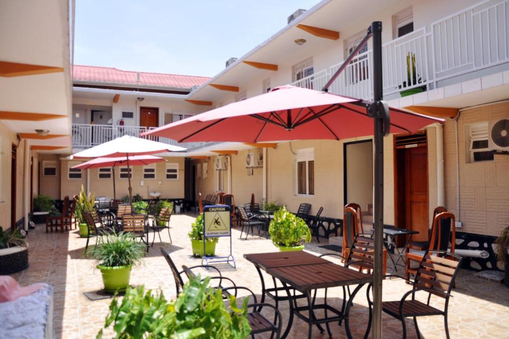 un patio esterno con tavoli, sedie e ombrelloni di Sandton Hotel Kasese a Kasese