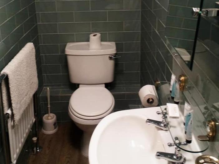 a green tiled bathroom with a toilet and a sink at Holland Hotel in Llanfachraeth
