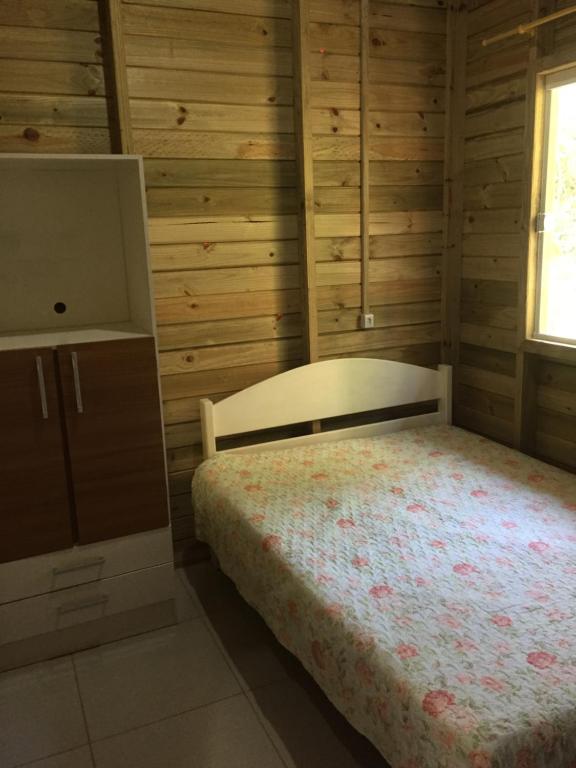 a bedroom with a bed and a cabinet and a window at Paraíso do Rosa in Praia do Rosa
