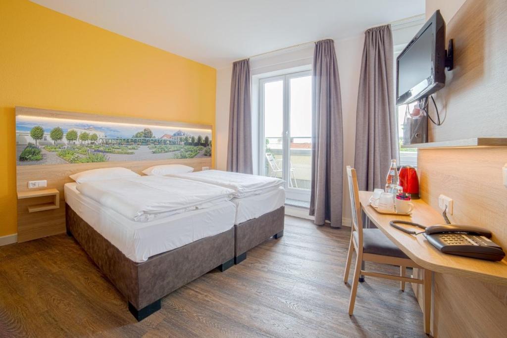 una camera d'albergo con letto e scrivania con computer di City Hotel Hannover ad Hannover