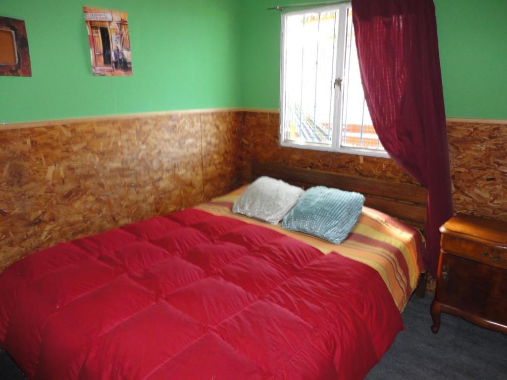 1 dormitorio con cama roja y ventana en Hostal Armando, en Valparaíso