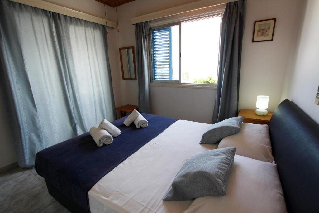 a bedroom with a large bed with pillows and a window at Pissouri Beach Apartments in Pissouri