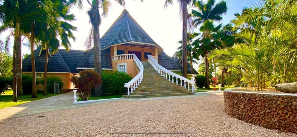 a house with stairs in front of a house with palm trees at Sunset Villa Boutique Resort in Diani Beach