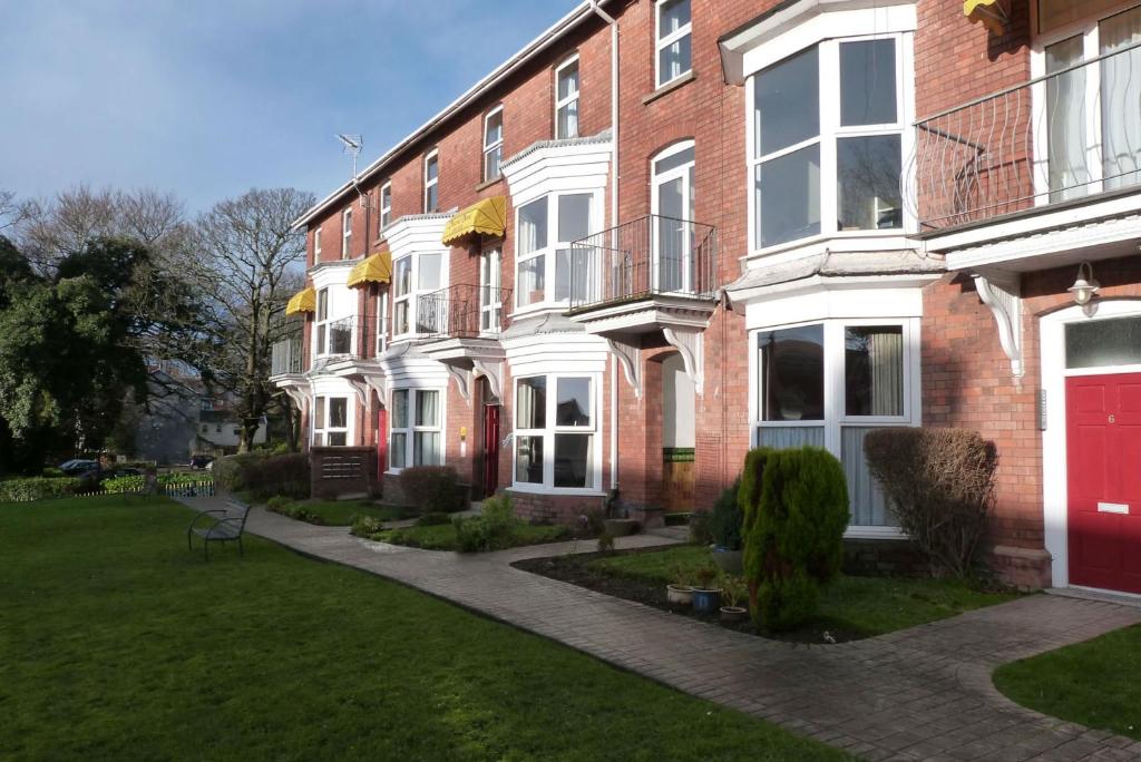 un gran edificio de ladrillo con puerta roja en Hurst Dene Aparthotel, en Swansea