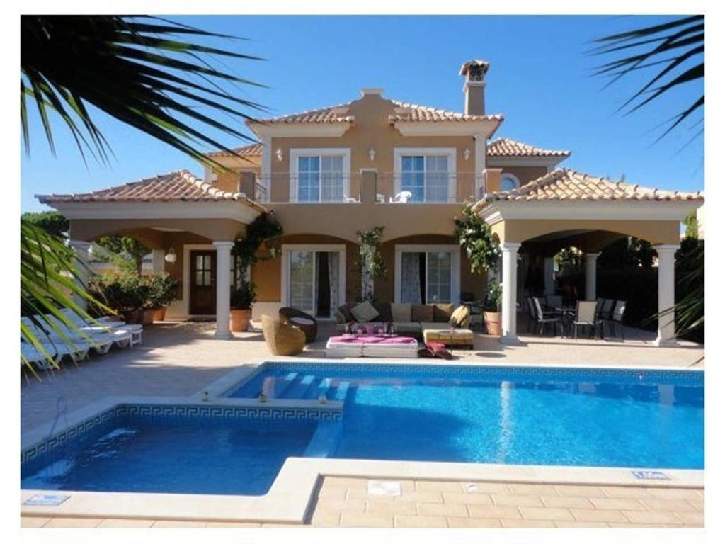 une maison avec une piscine en face d'une maison dans l'établissement Villa Varandas Do Lago - 5 Bedroom villa - Stunning pool area - Table tennis, à Vale do Lobo