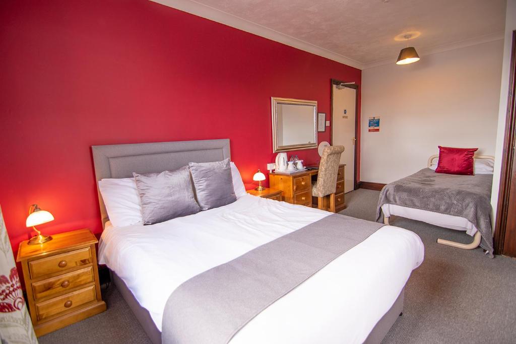 sypialnia z dużym łóżkiem i czerwoną ścianą w obiekcie The Station Guest House w mieście Woodbridge