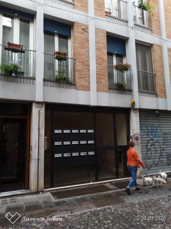 una mujer paseando a un perro delante de un edificio en barbarigo, en Padua