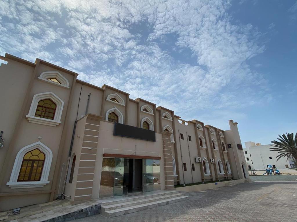 un grande edificio con un cielo nuvoloso sullo sfondo di Hotel Danat Al Khaleej a Ḩilf