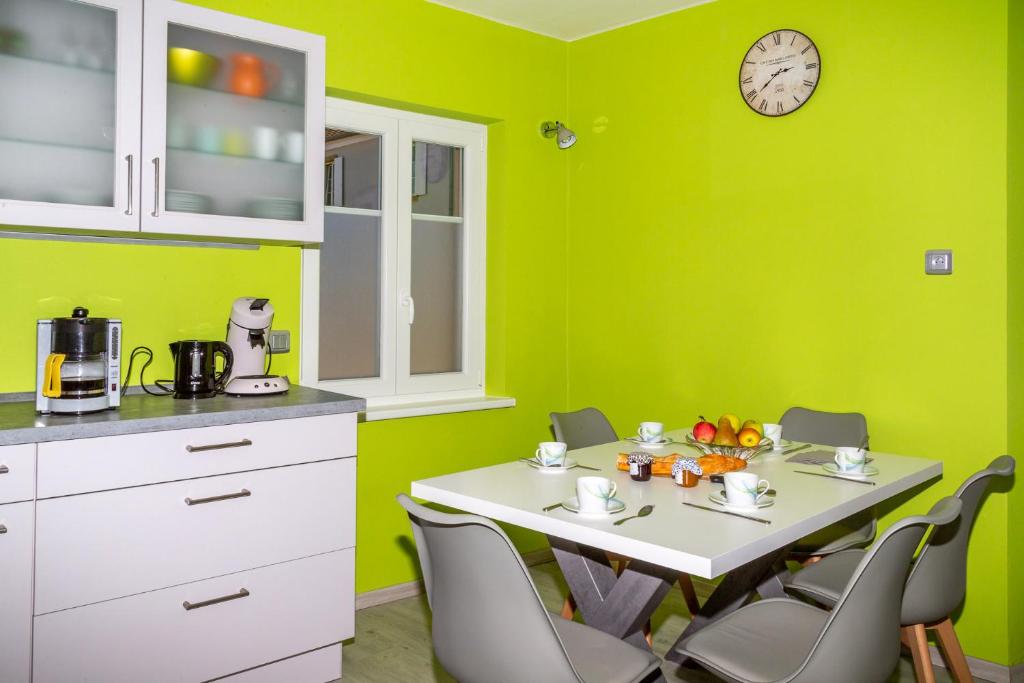 cocina con paredes verdes, mesa blanca y sillas en MA ROSE DES LUMIERES maison indépendante 6 personnes avec grande cour en Griesheim-près-Molsheim