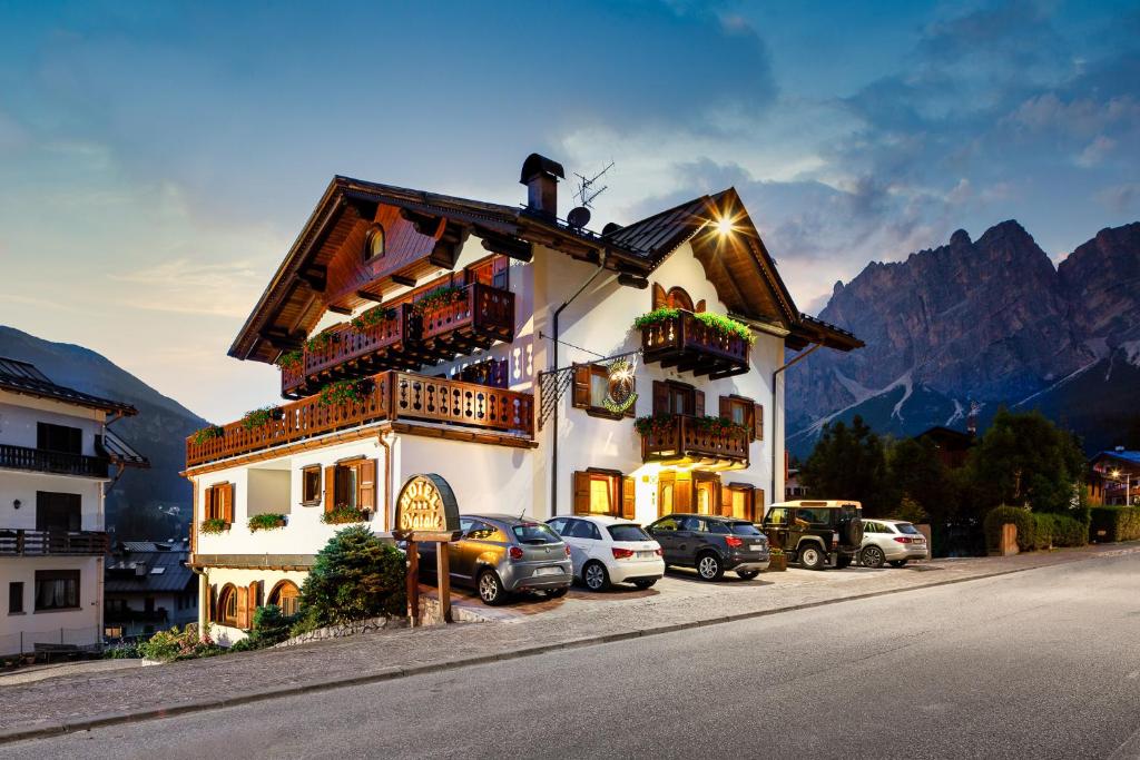 un bâtiment avec des voitures garées devant lui dans l'établissement Hotel Natale, à Cortina dʼAmpezzo