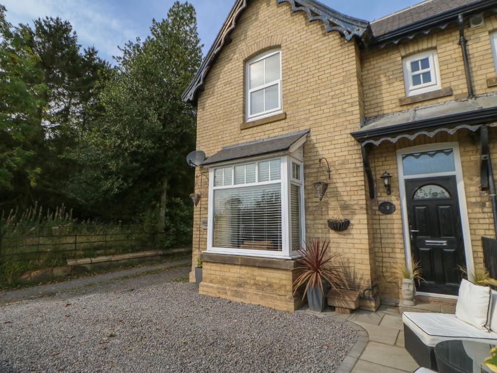 a brick house with a black door and a yard at 2 Drumrauch Cottages in Yarm