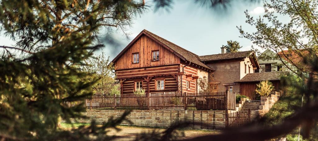 a wooden house with a fence in front of it at Roubenka u Huvarů in Tachov