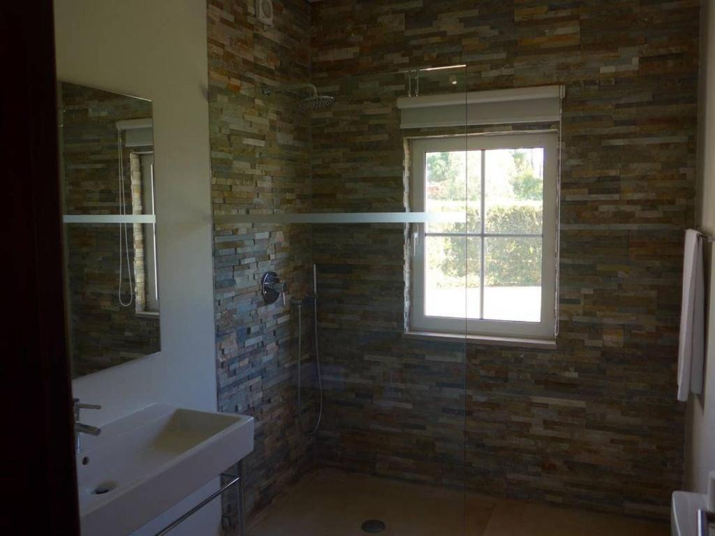 a bathroom with a brick wall and a window at Villa Sol Grande - Exclusive 5 Bedroom Villa - Great Pool Area - Perfect for Families in Quarteira