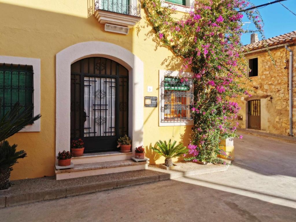La Guardiola的住宿－Joanet Guarda turismo familiar en plena naturaleza，黄色的建筑,有黑色的门和鲜花