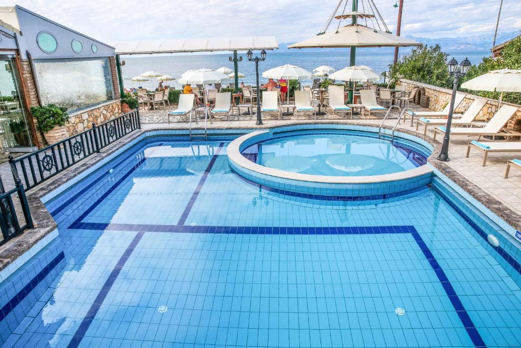 una piscina in un hotel con sedie e ombrellone di Navigator Villas - Houses ad Acharavi