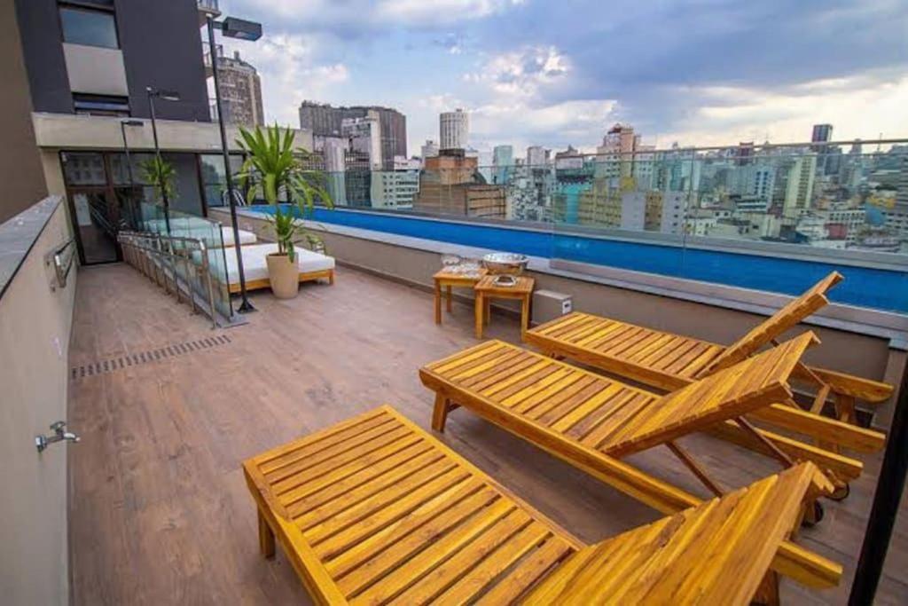 サンパウロにあるLindo Studio Arouche 711の木製の椅子が備わるバルコニーから市街の景色を望めます。