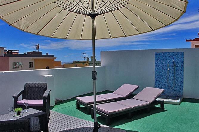 un patio con due sedie e un ombrellone di VV ATICO PUERTO TAZACORTE a Puerto