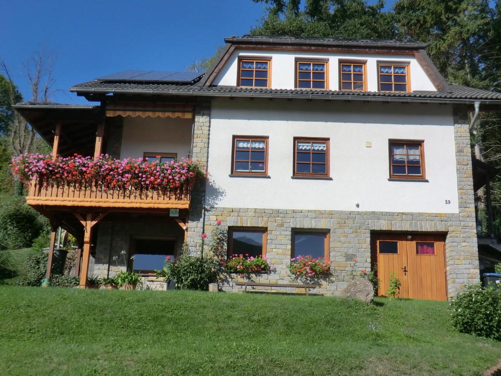 ein Haus mit einem Balkon mit Blumen darauf in der Unterkunft Ferienwohnung Sommer in Löf