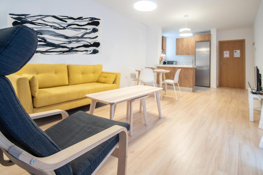 - un salon avec un canapé jaune et une table dans l'établissement Apartamento Colon en Cadiz, à Cadix