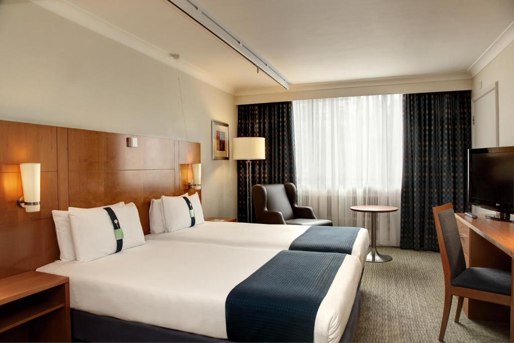 カーディフにあるホリデイ イン カーディフ シティの大型ベッドとテレビが備わるホテルルームです。
