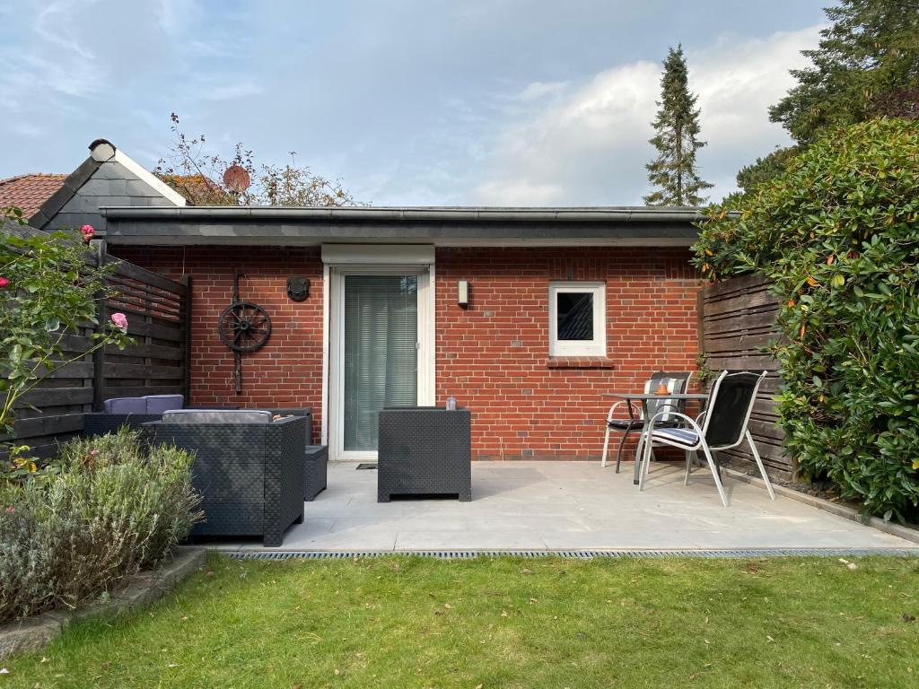 un patio con tavolo e sedie di fronte a una casa in mattoni di Haus Kogge Dangast a Varel