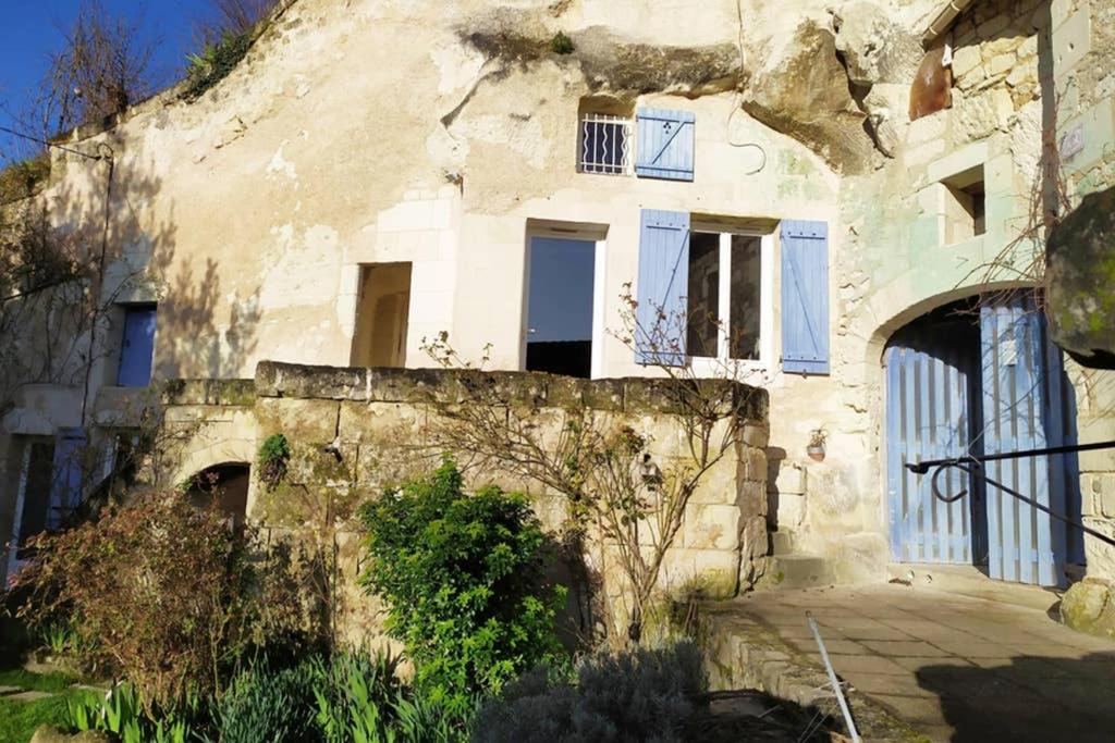 an old stone building with blue doors and windows at Le Refuge des Elfes in Bourré