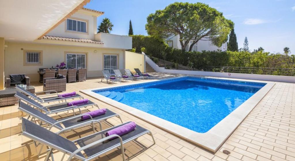 uma piscina com cadeiras e uma casa em Villa Povo do Burro beautiful and elegant villa few minutes walk to resort centre em Carvoeiro