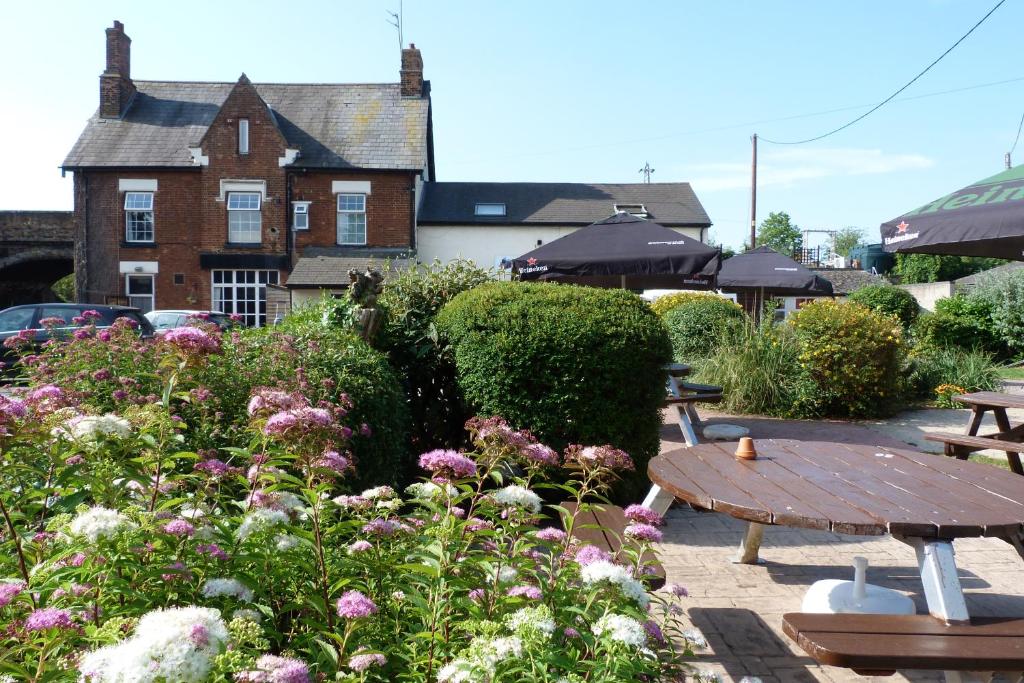 a garden with a wooden table and flowers in front of a building at Railway Inn in Culham