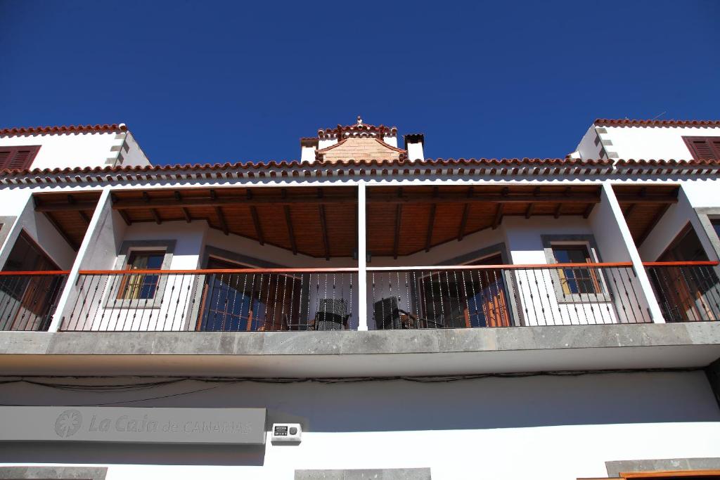 ein weißes Gebäude mit einem Balkon mit einem Dach in der Unterkunft VACACIONAL LA TEA THE BEST LOCATION and THE BEST VIEWS in Tejeda