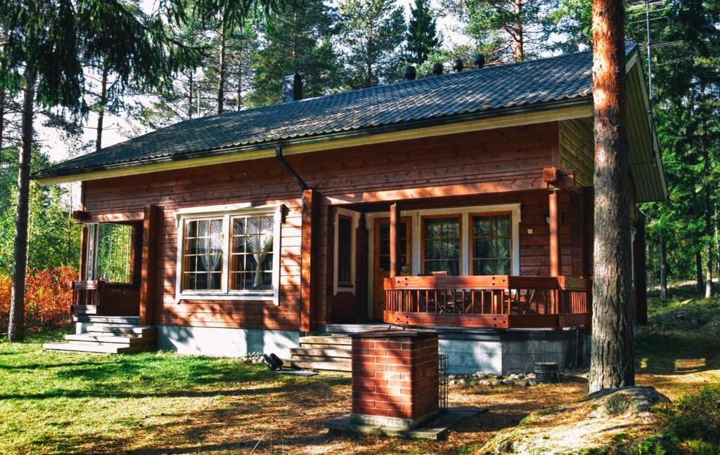 Cabaña de madera pequeña con porche y terraza en Honeyhill Villa Karhu, en Isnäs