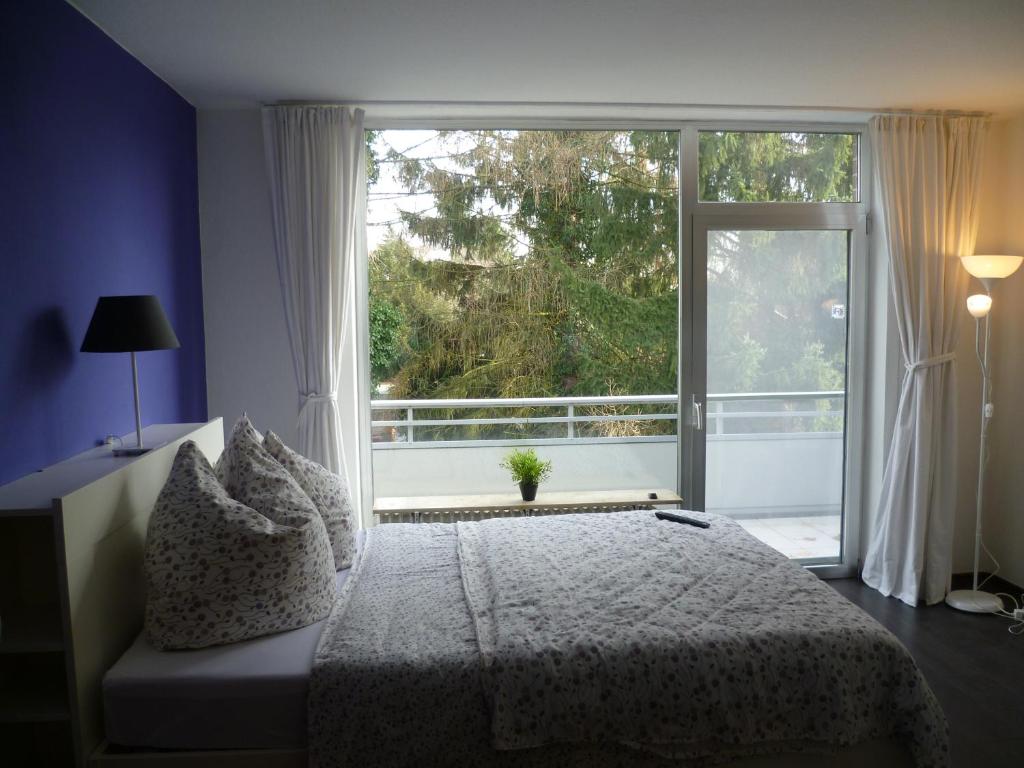 um quarto com uma cama e uma grande janela em Apartment am Park em Dusseldorf