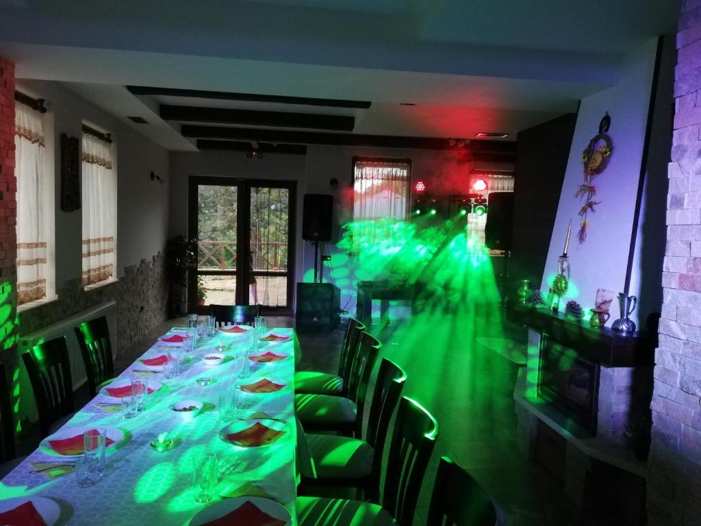 een lange tafel in een kamer met groene verlichting bij Къща за гости ДАЯНИЦА in Kopilovtsi