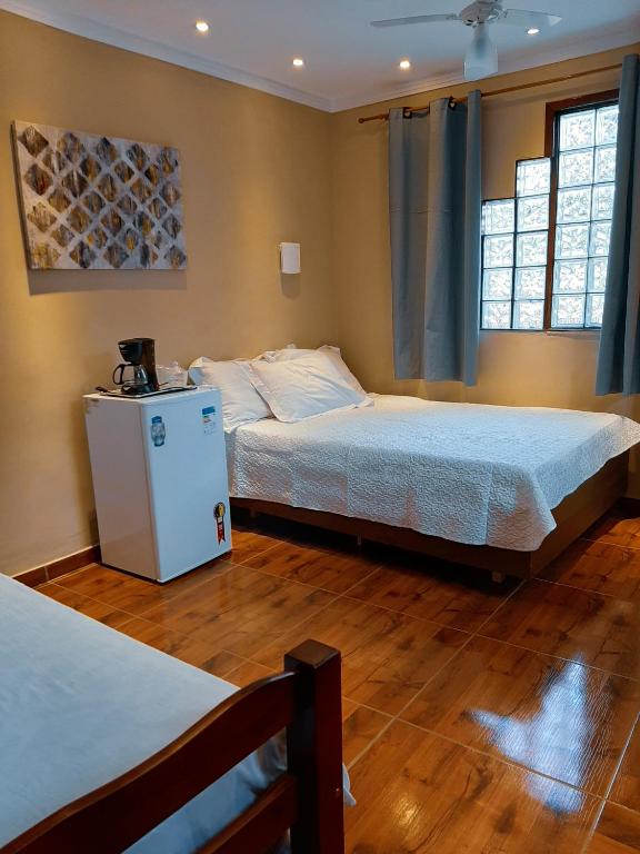 a bedroom with two beds and two windows at Suites Oliveira in Arraial do Cabo