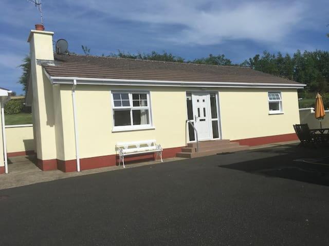 a small white house with a bench in front of it at Glenrandel Valley in Claudy