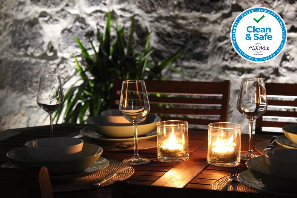 una mesa con copas de vino, platos y velas en Casa da Levada, en Ribeira Grande