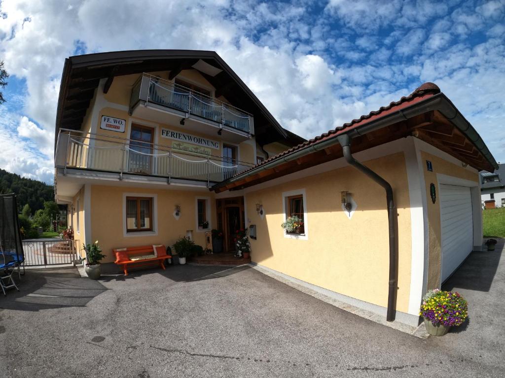 un grand bâtiment jaune avec un balcon au-dessus dans l'établissement Haus Hedwig, à Fuschl am See