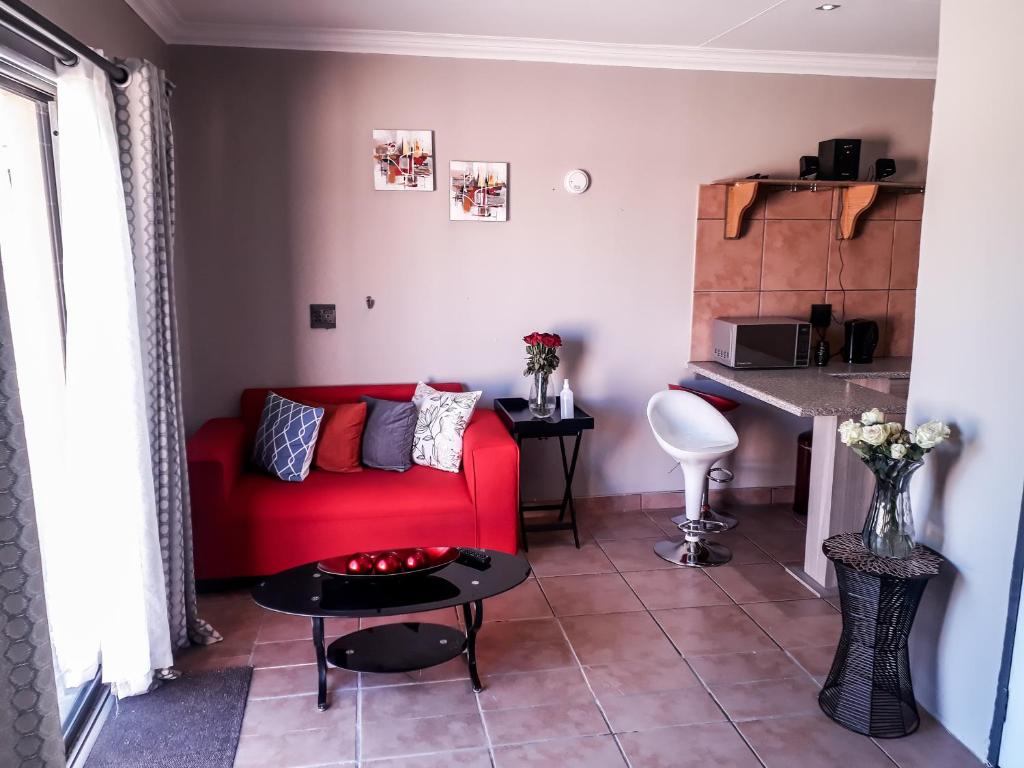 a living room with a red couch and a table at Quiet Getaway in Bloemfontein
