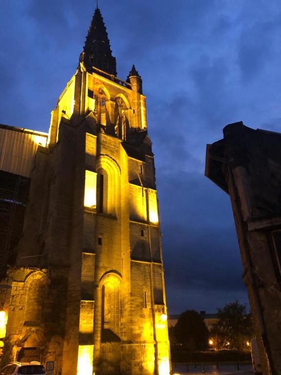 um edifício com uma torre de relógio à noite em Gîte St Thomas em Crépy-en-Valois