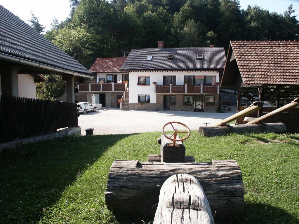 a yard with a log with a house in the background at Pri Lazarju Farm Stay in Podgrad